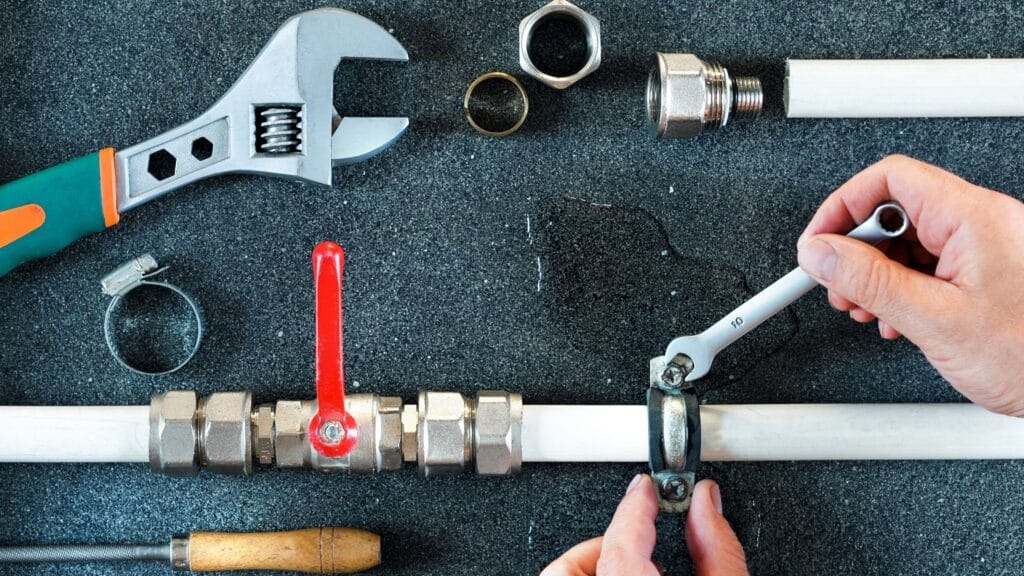 Plumber repairing a pipe valve with an adjustable wrench in West Chester