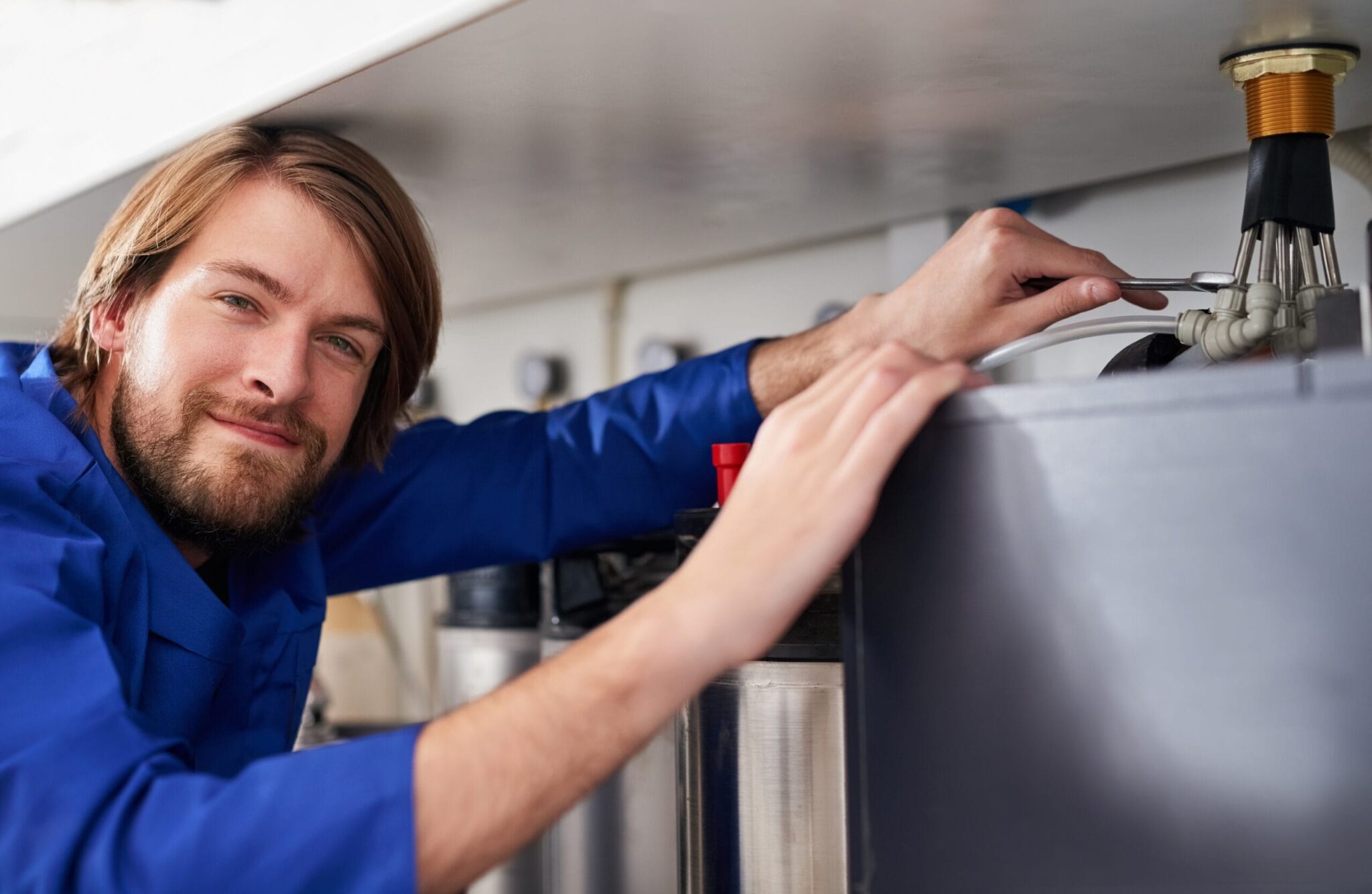 Technician servicing a residential water heater tank in West Chester